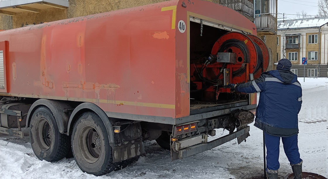 Каналопромывочная машина и работник прочищают засор в канализационной системе в Омске