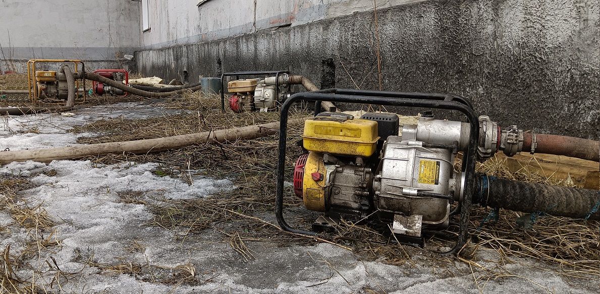 Откачка мотопомпами талой воды из подвала дома в Омской области